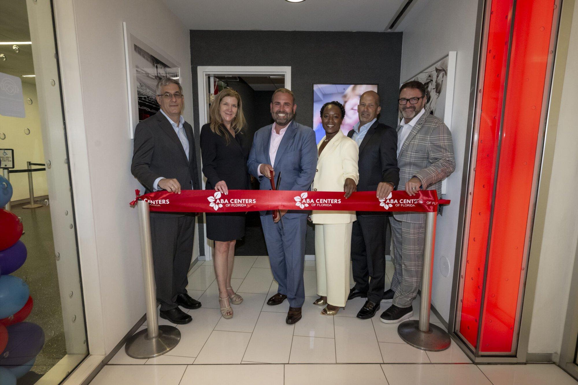 Barnett (center, blue jacket) cuts the ribbon at an ABA Centers of Florida clinic opening