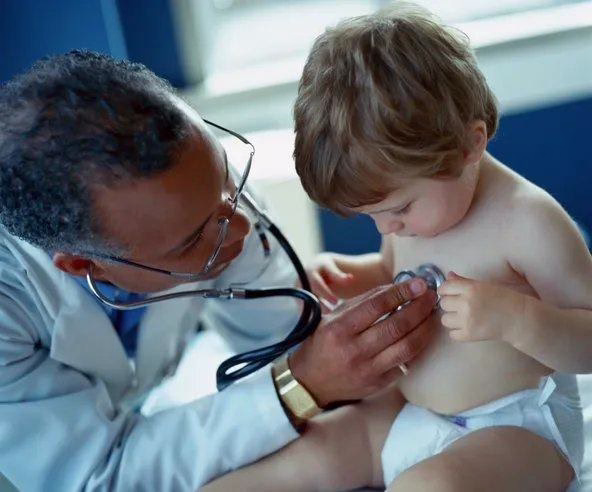 A pediatrician examines a toddler during a well-child visit