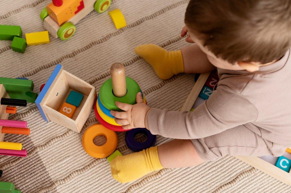 A toddler engages in play-based developmental activity. Early Start Denver Model intervention can begin as young as 12 months and is delivered in naturalistic home and childcare settings, requiring providers to adapt clinical models beyond traditional clinic-based ABA.