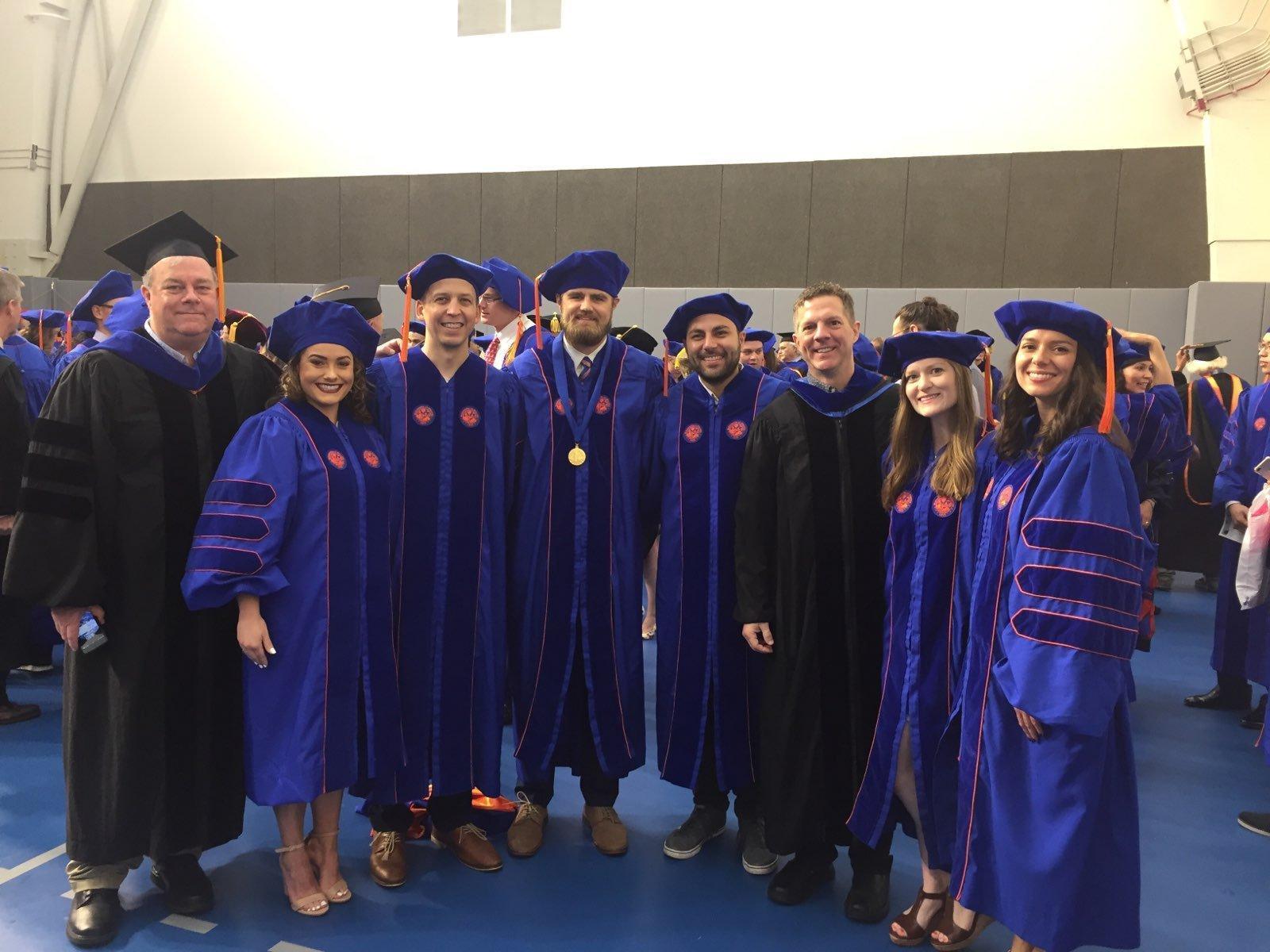 Vollmer (far left, in black faculty robes) at a University of Florida doctoral commencement ceremony with newly hooded PhDs from his program. The pipeline of UF behavior analysis doctoral students now leads research and clinical operations at universities, hospitals, and ABA providers across the country.