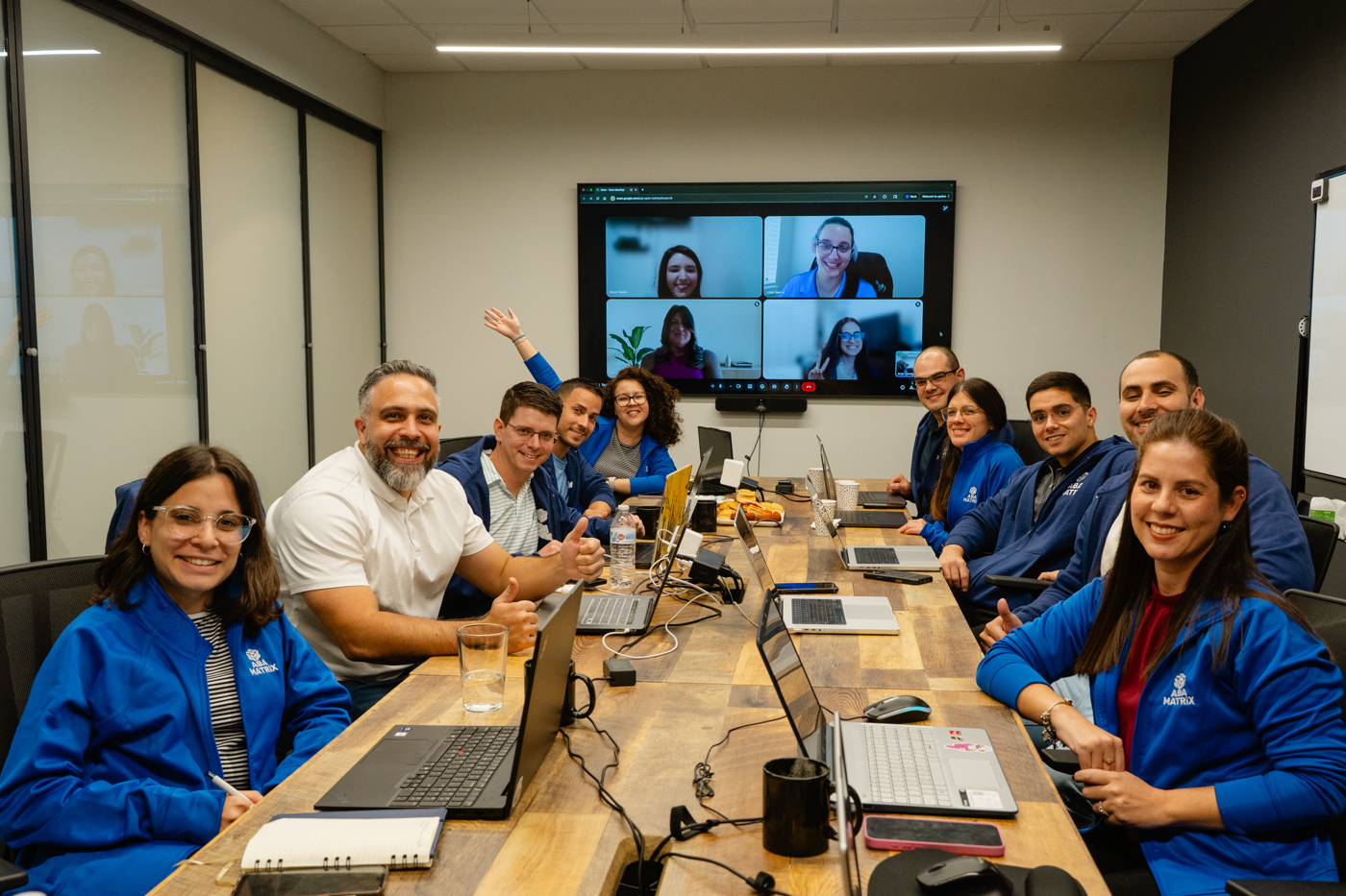 ABA Matrix staff meet around a conference table as remote colleagues join by video, July 2025. (Courtesy of ABA Matrix)